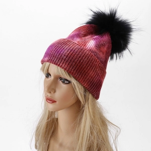 Detailed close-up of tie-dye pink and purple knit beanie with black faux fur pom-pom