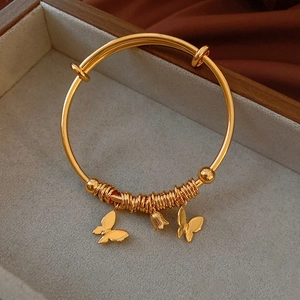 Detail of gold-plated butterfly bracelet with wire-wrapped charms and a lily bell