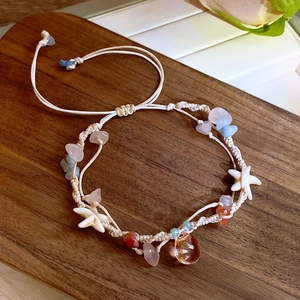 Detail of bohemian woven bracelet with colorful natural stones and starfish on wood