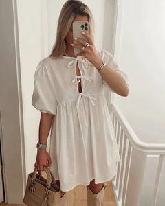 Detail eines weißen Babydoll-Kleides mit Puffärmeln und süßem Bindedesign an der Vorderseite