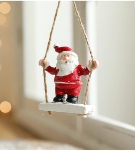 Detail of Santa Claus resin ornament on a swing with hemp rope and a white board base