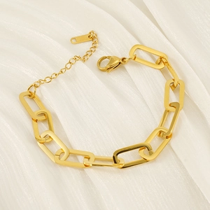 Détail macro du bracelet chaîne trombone plaqué or 18 carats sur un tissu blanc doux