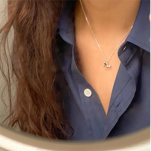 Minimalist 925 sterling silver whale necklace on a female model with blue shirt
