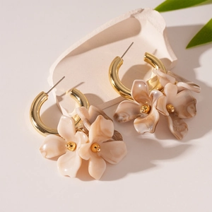 Gros plan de boucles d'oreilles créoles dorées avec pétales en acrylique marbré