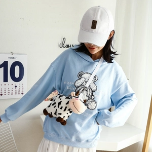 Cute cow pattern plush crossbody bag for children shown being worn by a model