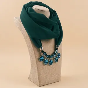 Dark green chiffon scarf necklace with blue gemstone pendant on a display mannequin