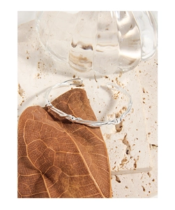 Detailed close-up of S925 sterling silver twisted knot cuff bracelet on brown leaf