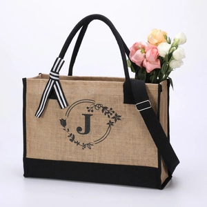 Detail of jute tote bag with black canvas trim, letter J floral print, and striped ribbon