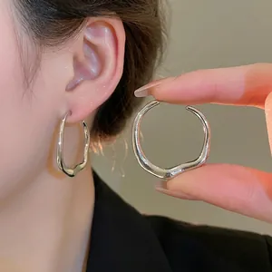 Irregular wavy silver hoop earrings with minimalist polished organic metal design