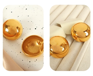Macro shot of gold spherical stud earrings showing polished finish and texture details