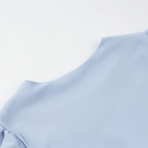 Detail of light blue short sleeve top featuring refined chiffon fabric and neckline tailoring