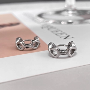 Macro shot of polished silver figure-eight interlocking link earrings on magazine backdrop