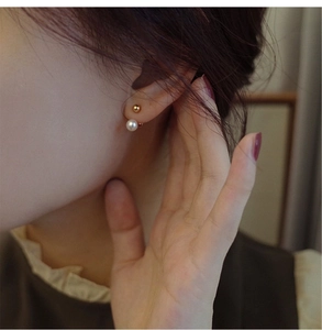 Detail shot of dainty freshwater pearl and 18K gold ball studs worn on earlobe