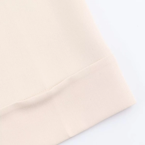 Macro view of beige trousers featuring detailed folded hem and fine fabric texture
