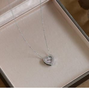 Close-up of a silver heart pendant necklace with rhinestones in a beige jewelry box