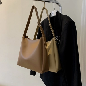 Minimalist leather tote bag with adjustable wide shoulder strap shown in a studio setting