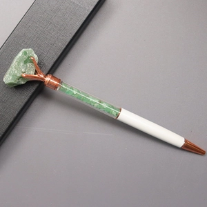Detail of white metal ballpoint pen with green crystal stone filling and rose gold finish