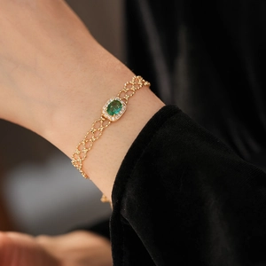 Detailed close-up of a vintage gold bracelet featuring an oval green gemstone and zircons