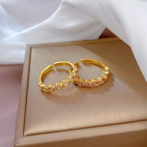 Minimalist gold plated open rings with white and pink zircon crystals on jewelry box