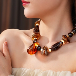 Dettaglio della collana vintage in resina ambra su modella con accenti in metallo oro
