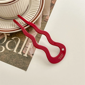 Detailed shot of a red wavy U-shaped acetate hair pin with sparkling rhinestone detail