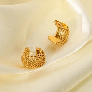 Detail of 18k gold plated C-shaped mesh earrings on beige silk fabric background