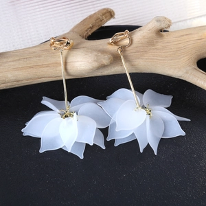 Macro detail of white translucent petal pendant clip-on earrings on wood branch