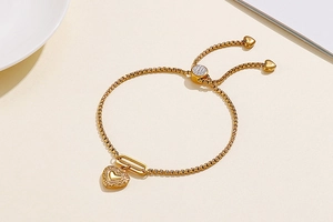 Detail of adjustable gold heart charm bracelet with slider clasp and square link chain