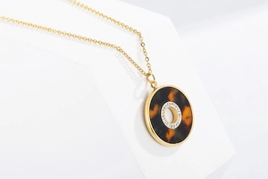 Detail of round gold pendant necklace with leopard pattern and sparkling rhinestones
