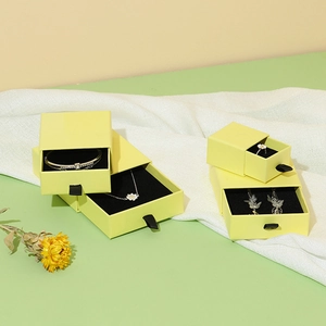 Elegant yellow drawer-style jewelry boxes in various sizes with black ribbon handles