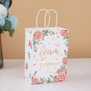 Detail of white kraft gift bag with gold foil Team Bride text and pink rose patterns