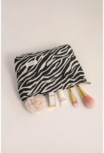 Close-up of zebra pattern canvas makeup bag with lipstick, brushes and floral detail
