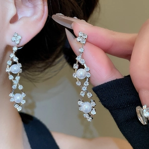 Detail of silver drop earrings with sparkling diamonds and elegant white pearls