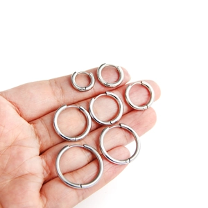Titanium steel hoop earrings in seven various sizes shown on a palm for scale