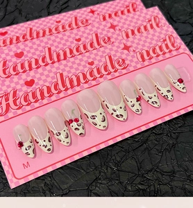 Detailed view of handmade almond nails with French leopard print and cherry rhinestones