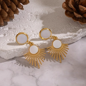 French vintage gold sunburst earrings with white shell inlay on a marble background