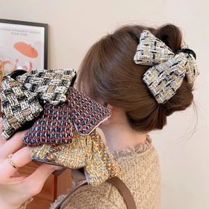 Vue détaillée d'une pince à cheveux avec nœud en tissu à carreaux et texture tweed