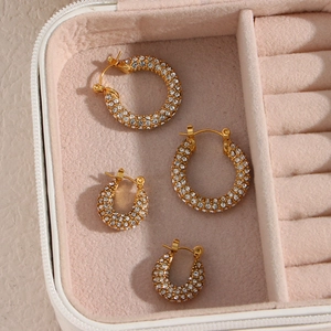 Close-up of gold U-shaped hoop earrings with pave cubic zirconia on pink velvet