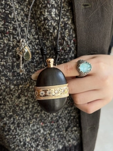 Detail of vintage wooden teapot pendant necklace with gold accents on leather cord