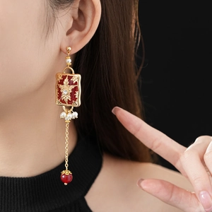 Detail of vintage red rectangle earrings with gold floral relief and pearl tassels