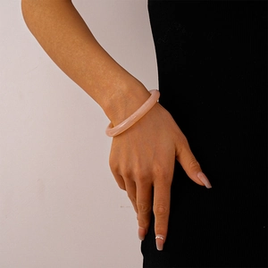 Detail of pink acrylic resin bangle with marble texture worn by a model in lifestyle shot