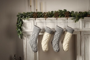 Detail of grey and ivory cable knit Christmas stockings hanging on a fireplace mantel