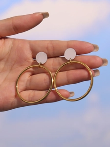 Détail des créoles bicolores de 4cm en or et argent tenues à la main par le sujet