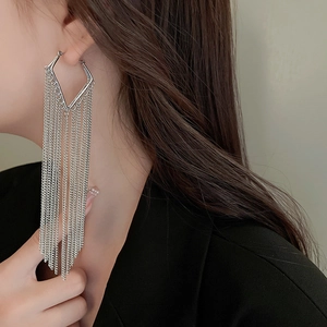 Macro detail of silver long tassel chain earrings showing geometric rhombus design