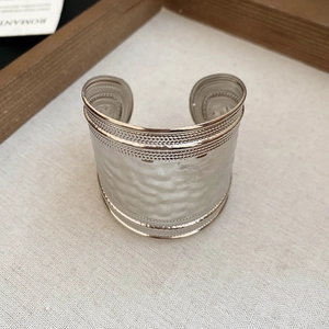 Détail d'un bracelet jonc argenté avec texture martelée et bords perlés fins