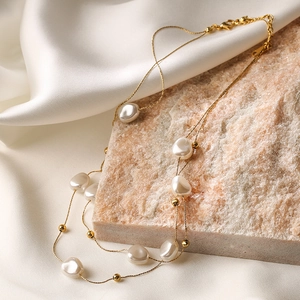 Elegant gold chain necklace with white Keshi pearls on silk fabric for a luxury aesthetic