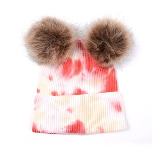 Détail du bonnet en tricot tie-dye multicolore avec doubles pompons doux et bordure côtelée