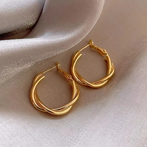Detail of golden twist rope hoop earrings displayed on premium silver satin fabric