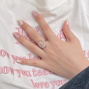 Detailed view of a vintage silver cameo ring with a pink oval portrait on a model's finger