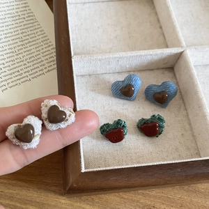 Detailed view of tweed heart-shaped earrings in white blue and green with bear motifs